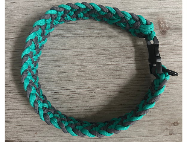 Braided green and gray dog collar on a wooden surface
