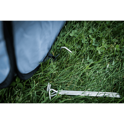 Metal tent stakes on grass with a blue tent partially visible