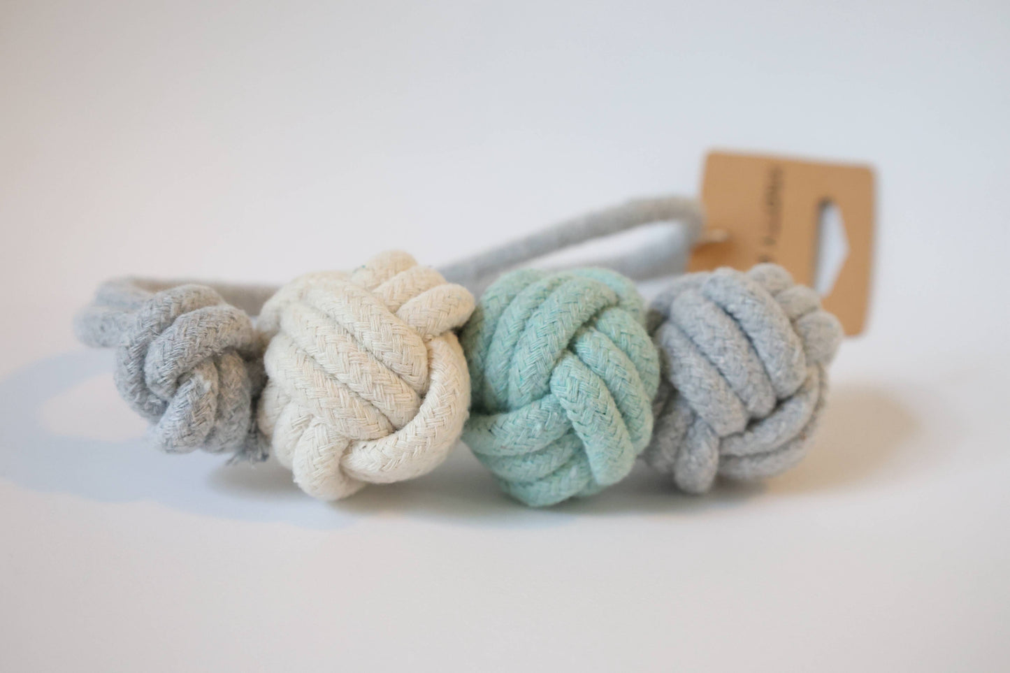 Three knotted fabric dog toys in pastel colors on a white background