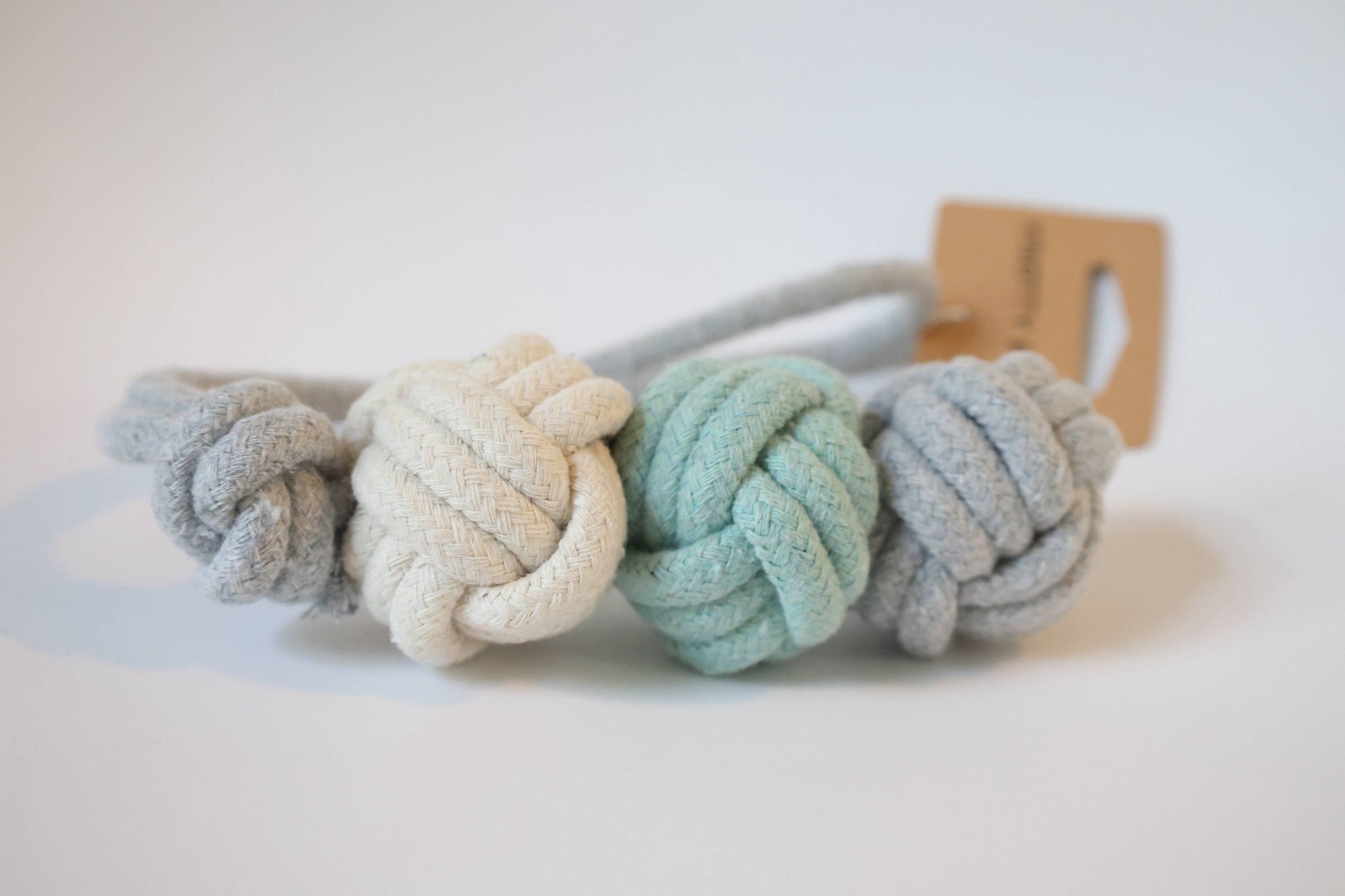 Three knotted fabric dog toys in pastel colors on a white background