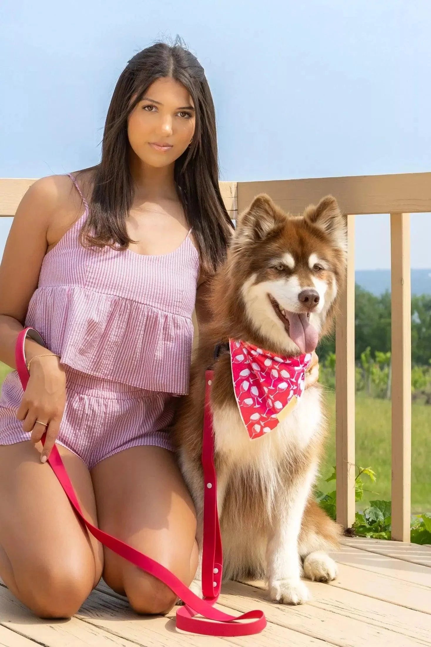 Woman in pink outfit with a dog on a leash on a wooden deck