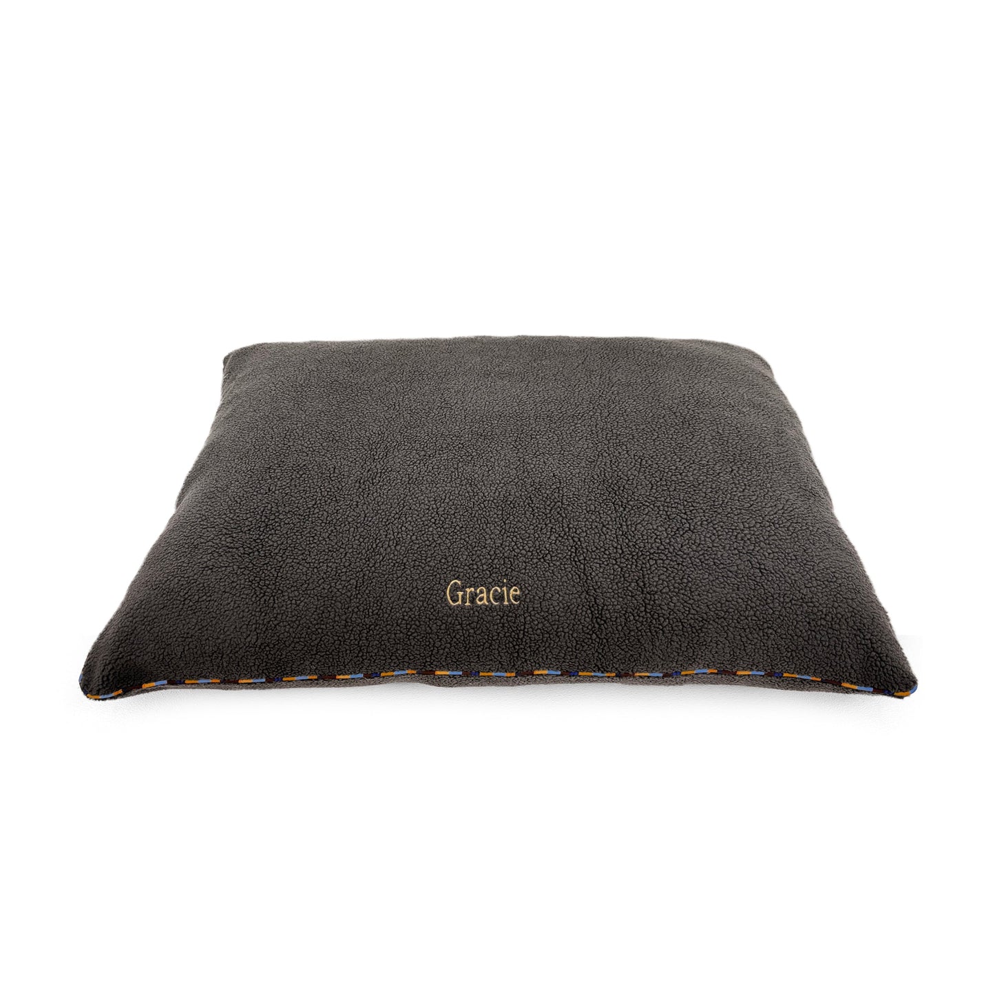 A dark gray plush pet bed with the name 'Gracie' embroidered in gold on the front, shown on a plain white background.