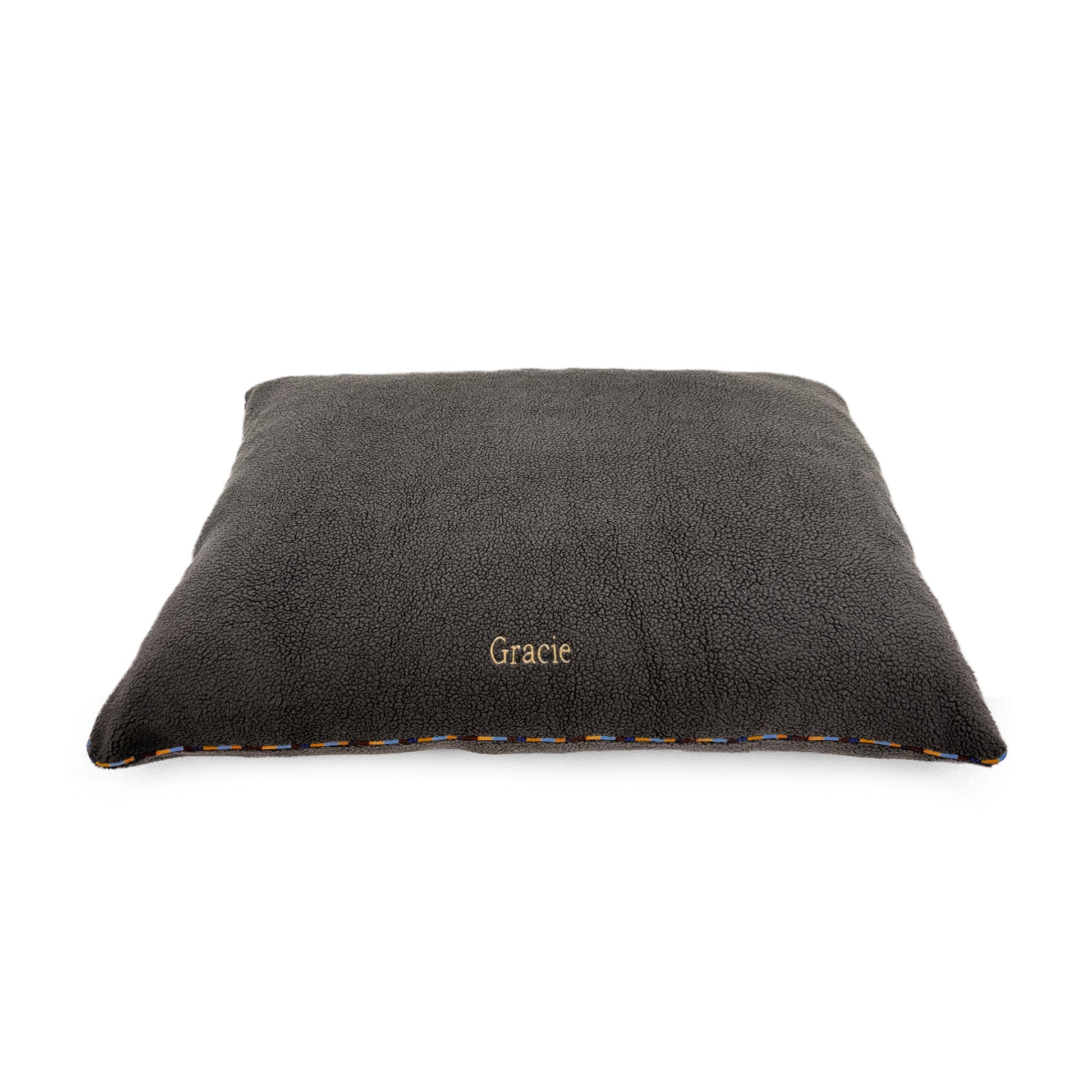 A dark gray plush pet bed with the name 'Gracie' embroidered in gold on the front, shown on a plain white background.