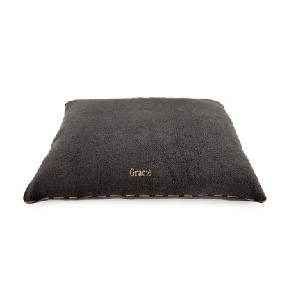 A dark gray plush pet bed with the name 'Gracie' embroidered in gold on the front, shown on a plain white background.