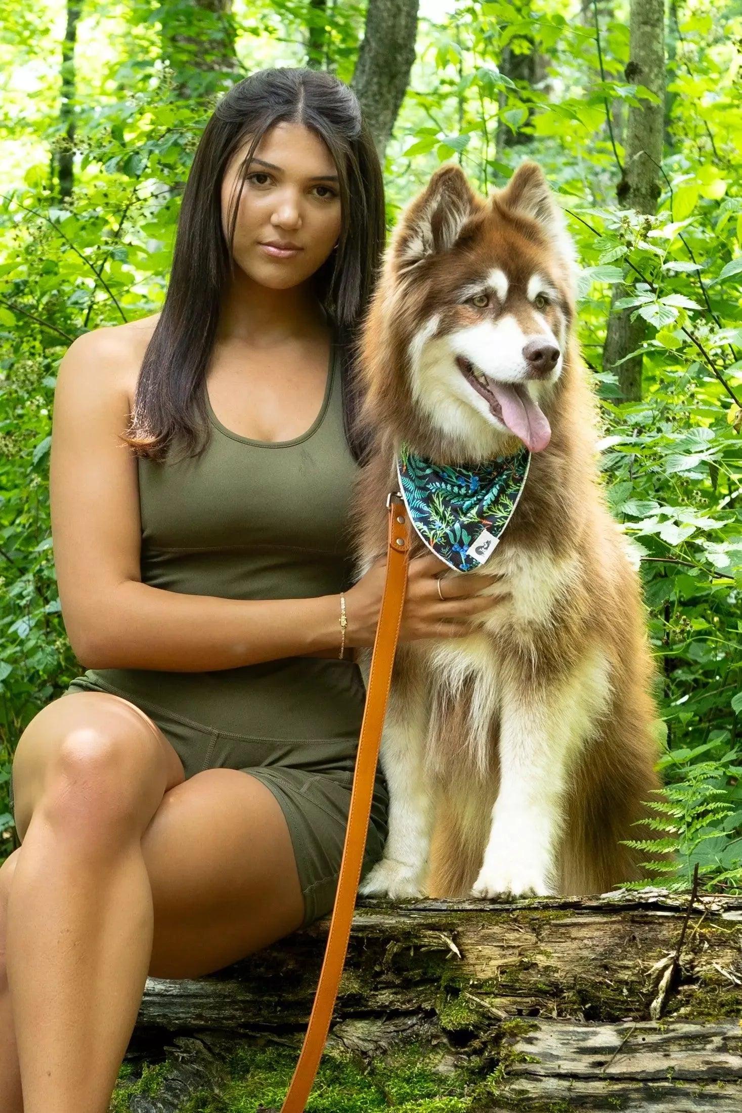 Woman sitting with a dog on a log in a forest