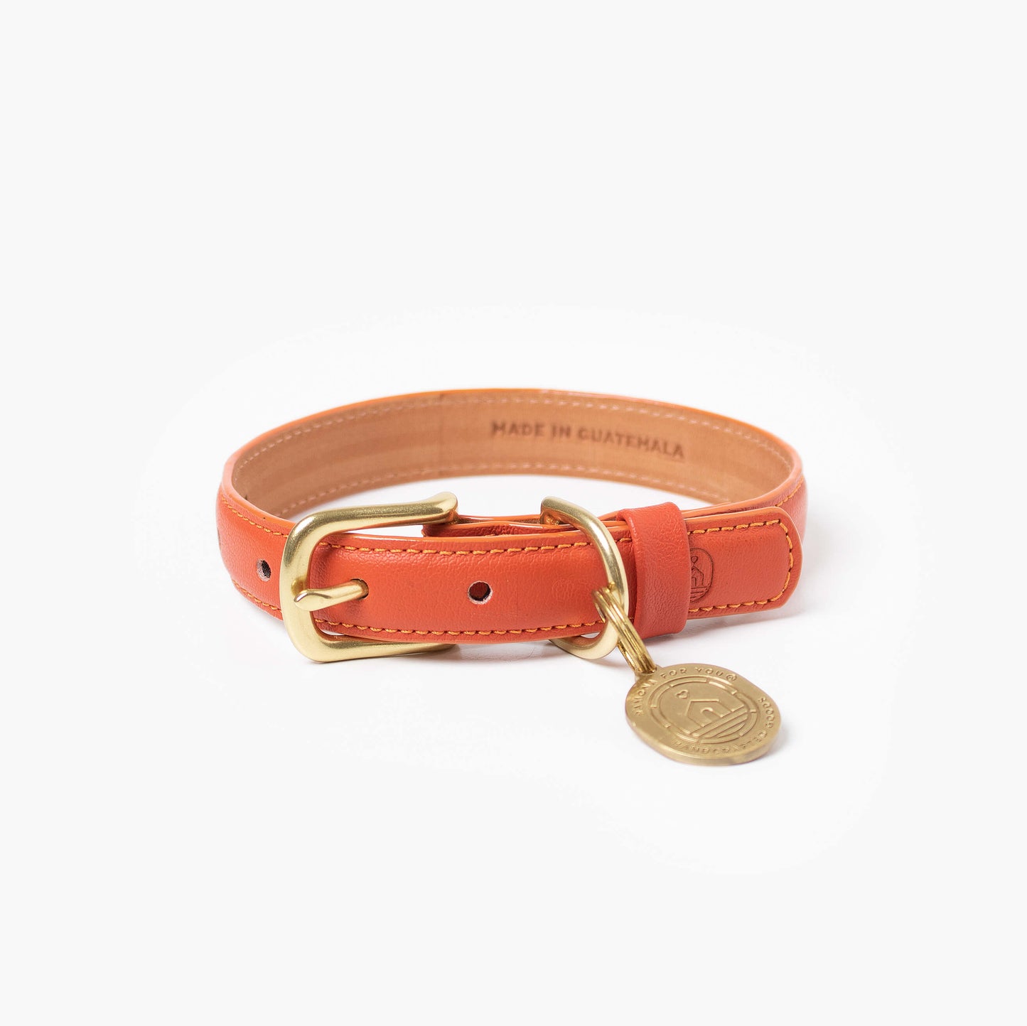 Orange leather dog collar with gold buckle and tag on a white background