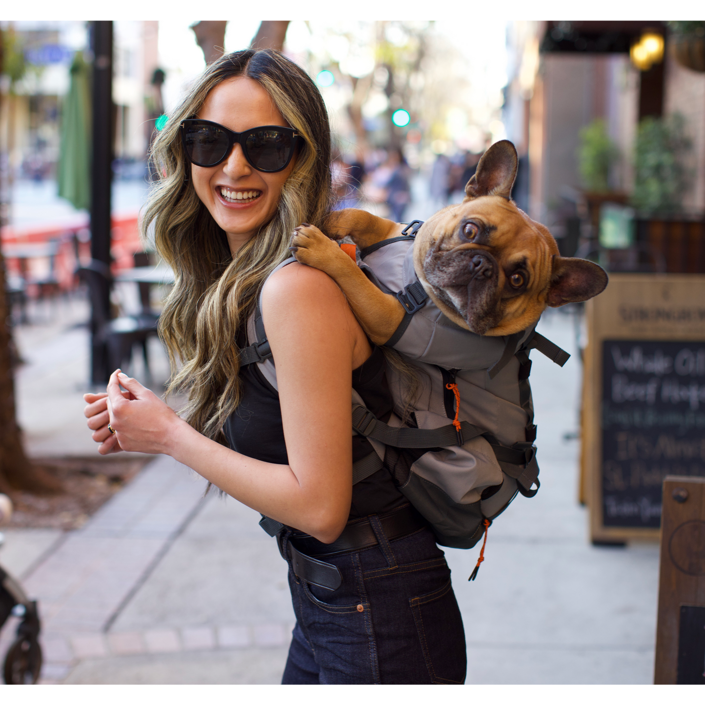 Woman carrying a small dog in a backpack on a city street