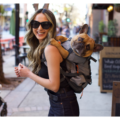 Woman carrying a small dog in a backpack on a city street
