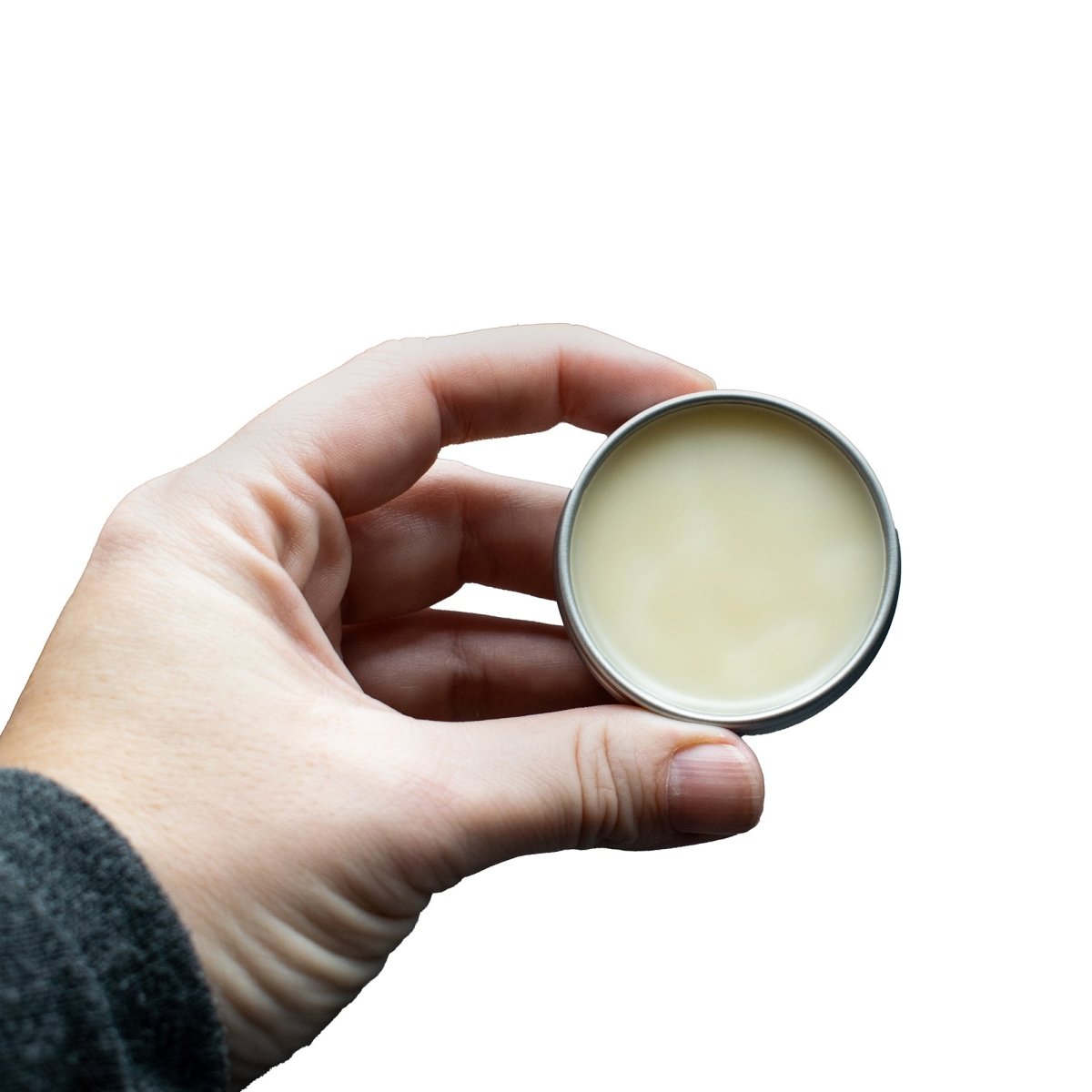 Hand holding a small round container of cream against a white background