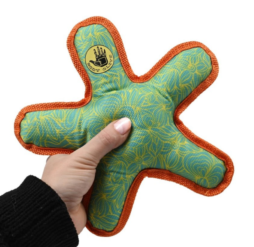 Hand holding a star-shaped green and orange toy with a brand logo on a white background