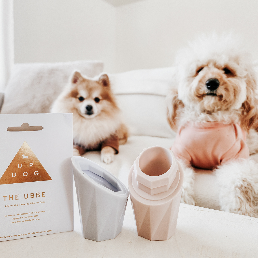 Two dogs sitting on a couch with a product packaging labeled 'UP DOG THE UBBE' in the foreground.