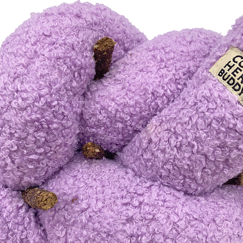 Purple textured dog tow with dog treats tucked in with a visible brand label on a white background