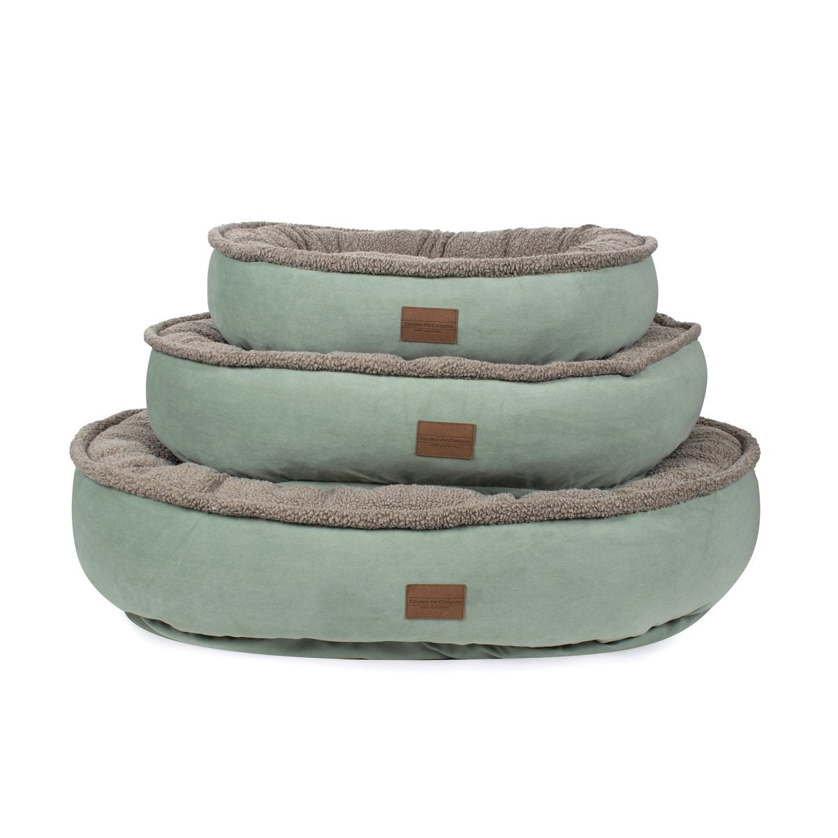 Set of three green pet beds with brown trim on a white background