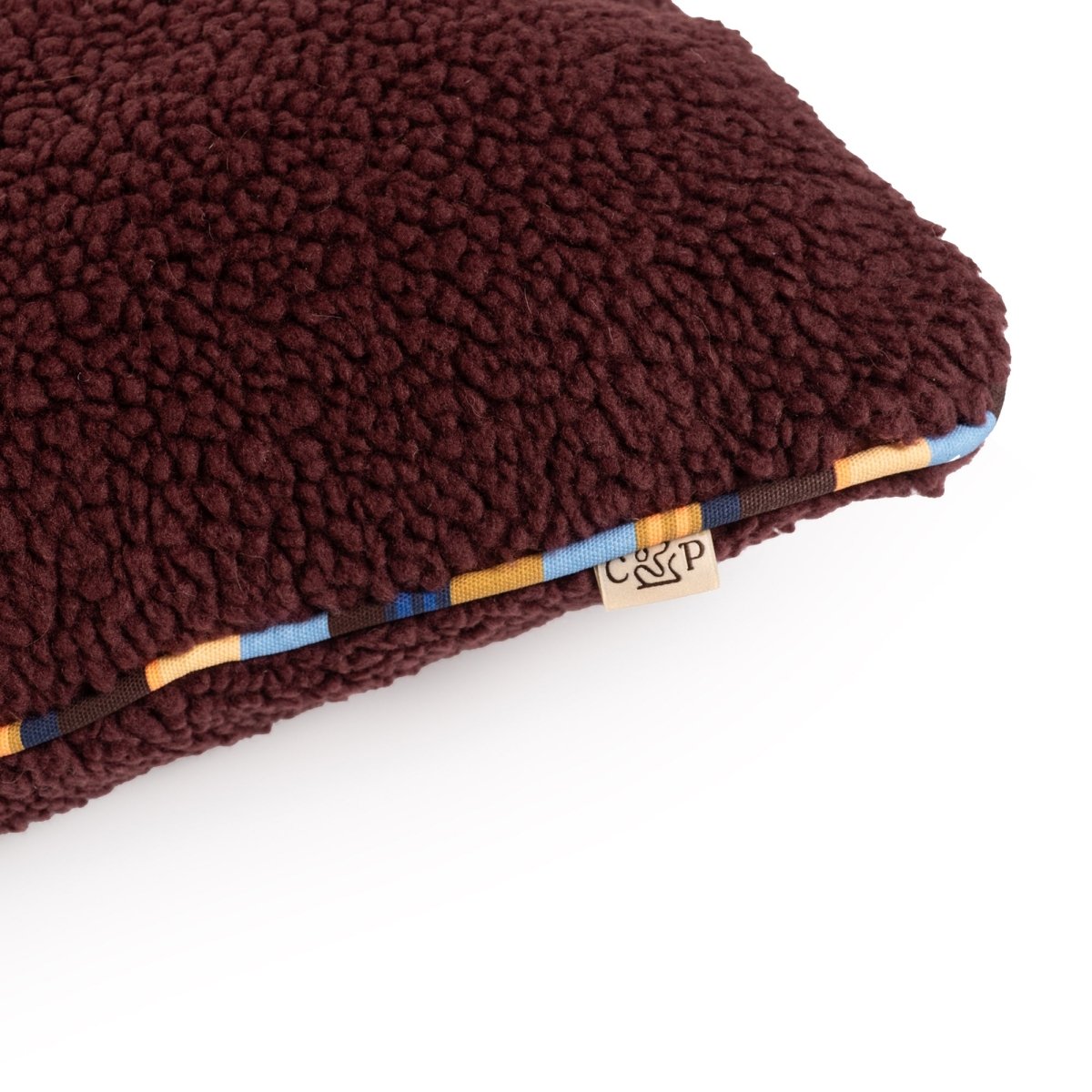 Brown textured pillow with a brand tag on a white background