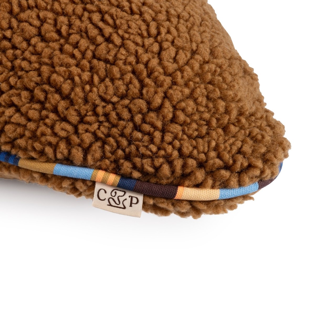 Brown sherpa fabric product with a brand label on a white background