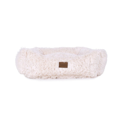 White fluffy dog bed with a brown label on a white background