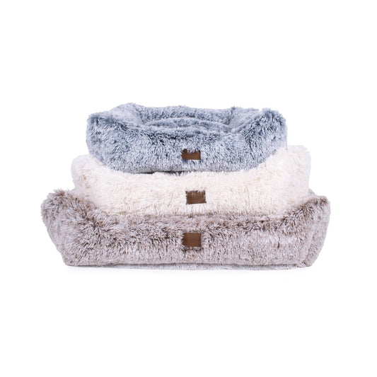 Stack of three fluffy pet beds in gray, white, and brown on a white background